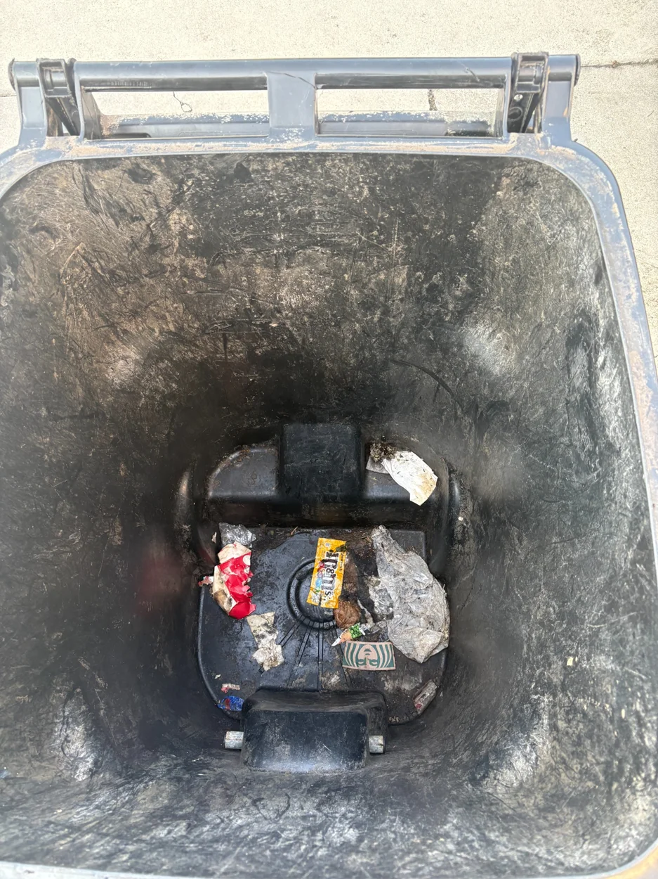 Black trash bin before cleaning, with residue inside